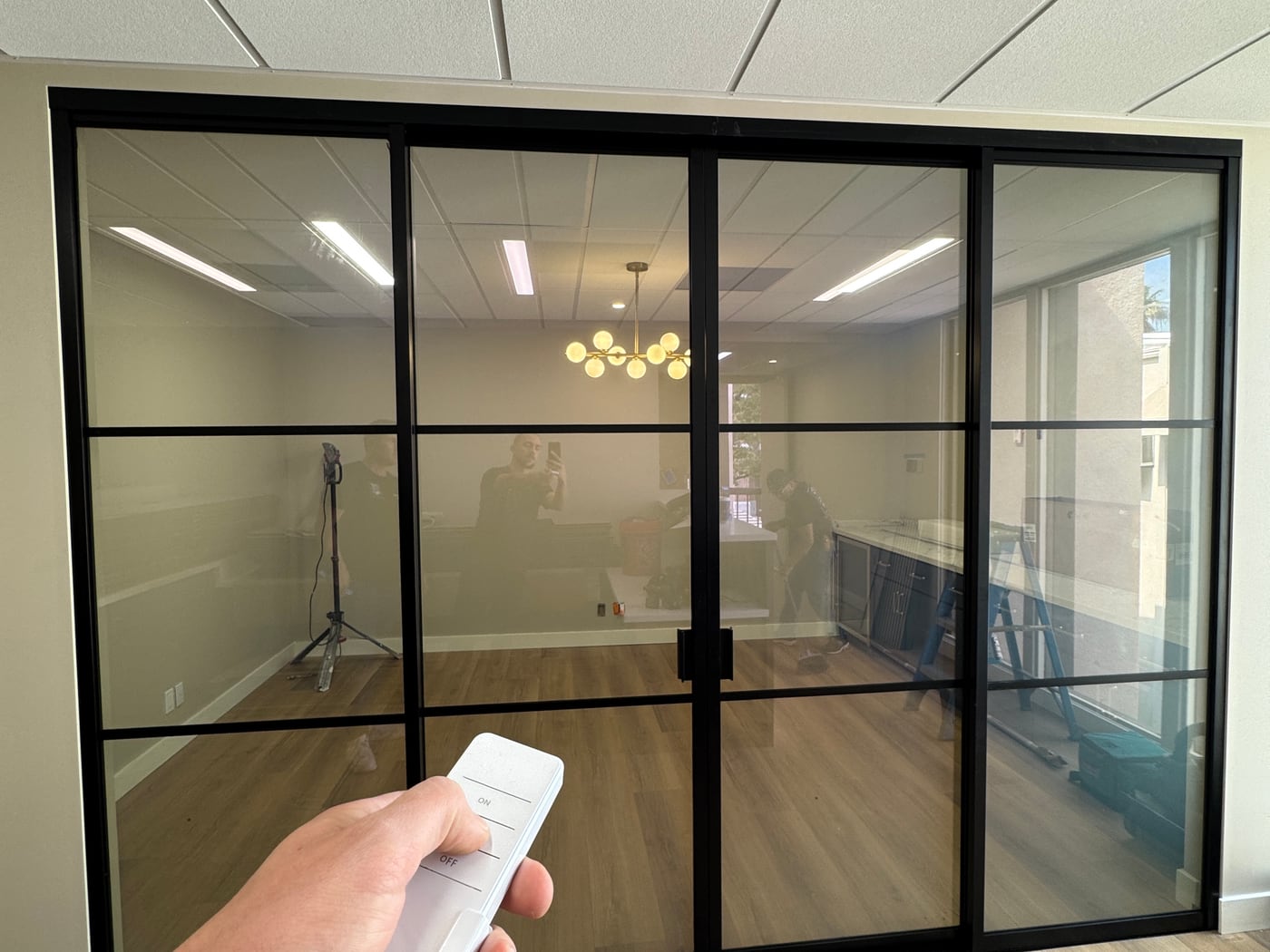 Black-grid smart glass partition switched clear, looking into the office